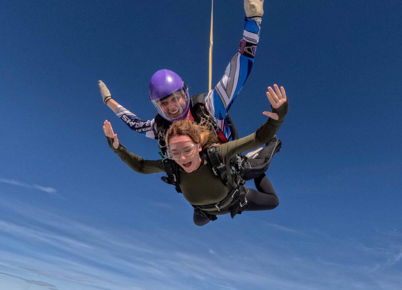 A skydiver smiles whilst in the air