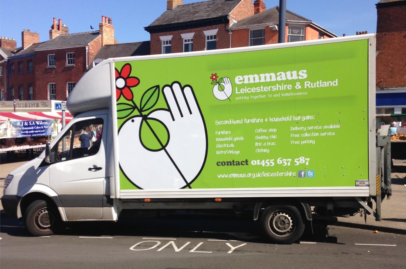 Emmaus Leicestershire & Rutland branded van parked on a street, with a large green panel displaying the Emmaus logo, contact information, and a list of services offered.